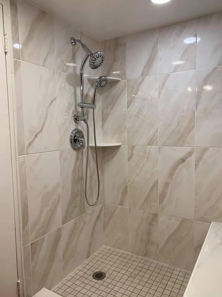 Walk-in shower with large-format white marble-look porcelain wall tile and chrome fixtures